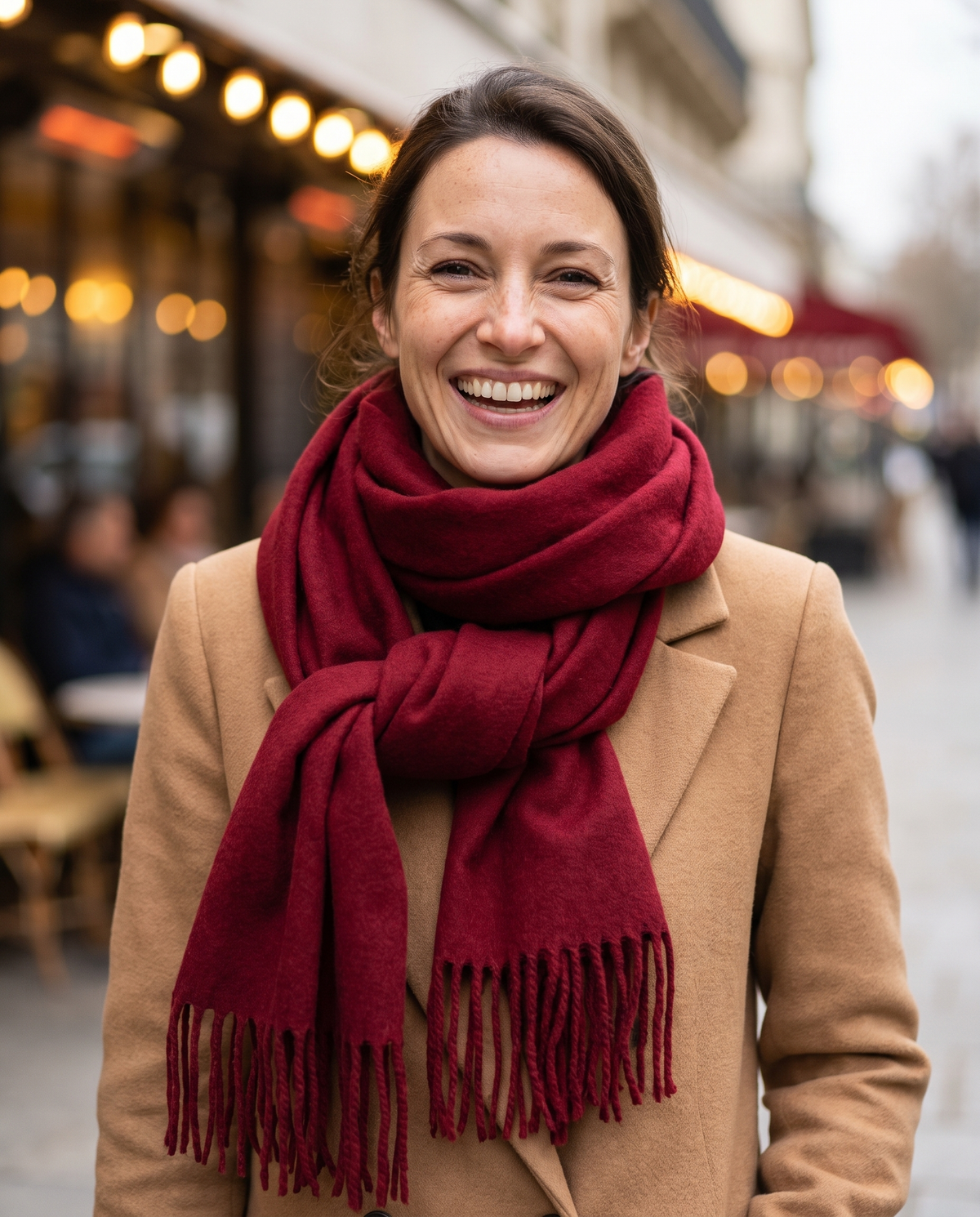 Une femme souriante portant l'écharpe bordeaux à franges